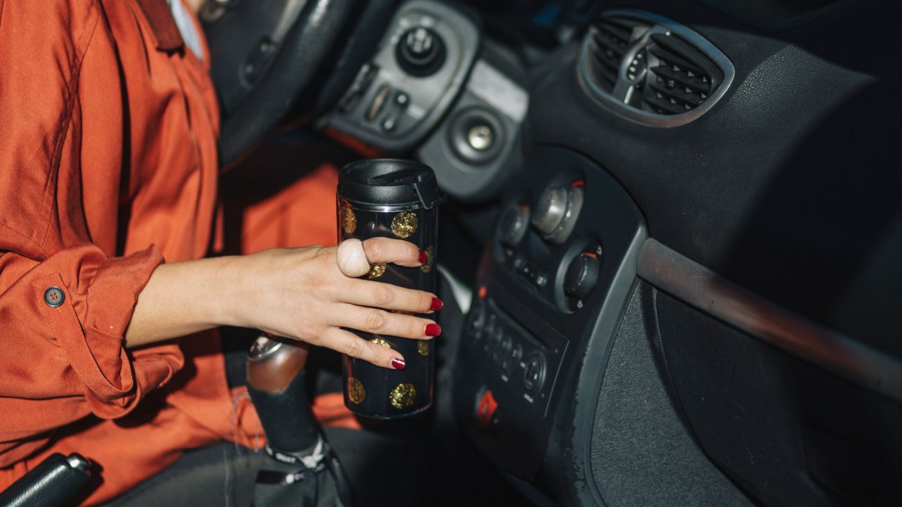 na foto uma mulher segura uma garrafa de água, um dos objetos soltos no carro que podem ser um perigo invisível de acidentes na foto uma mulher segura uma garrafa de água, um dos objetos soltos no carro que podem ser um perigo invisível de acidentes