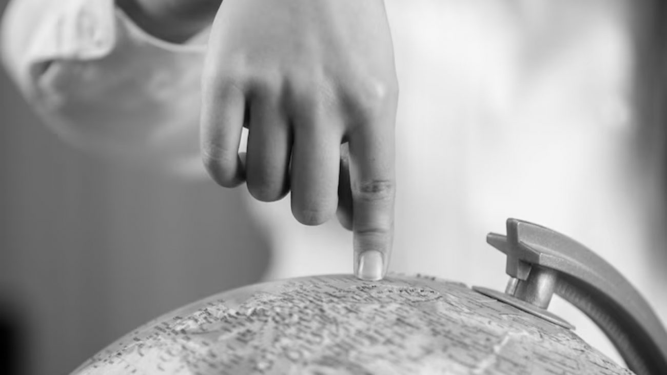 Pessoa apontando para planeta Terra em cima de globo