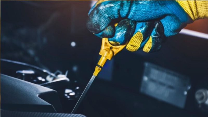 na moto aparece um mecânico medindo o nível do óleo do motor do carro com uma vareta na moto aparece um mecânico medindo o nível do óleo do motor do carro com uma vareta