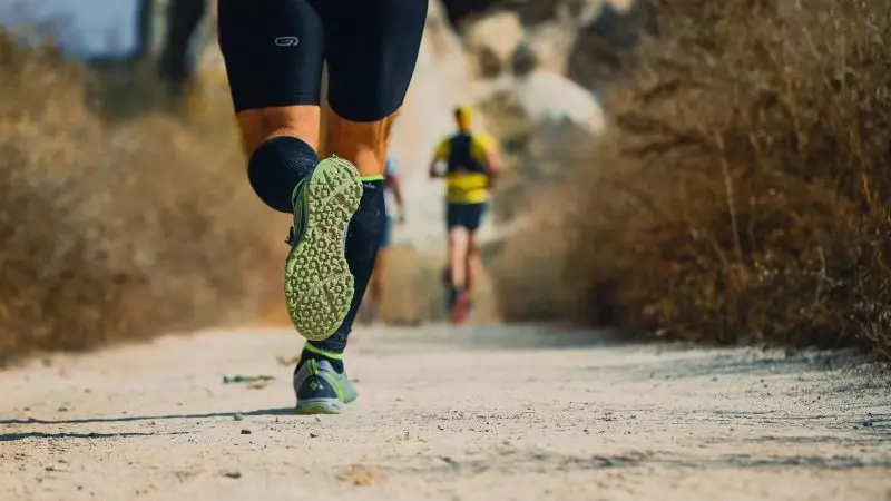 Corrida traz vários benefícios Imagem de trás das pernas de um homem correndo em uma pista de chão para ilustrar a matéria que explica sobre correr ou caminhar.