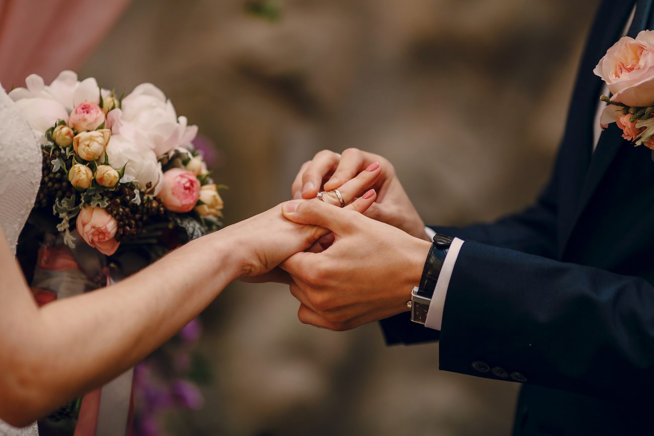 Foto de um homem colocando aliança na mão de uma mulher para ilustrar matéria sobre casamento coletivo em Criciúma