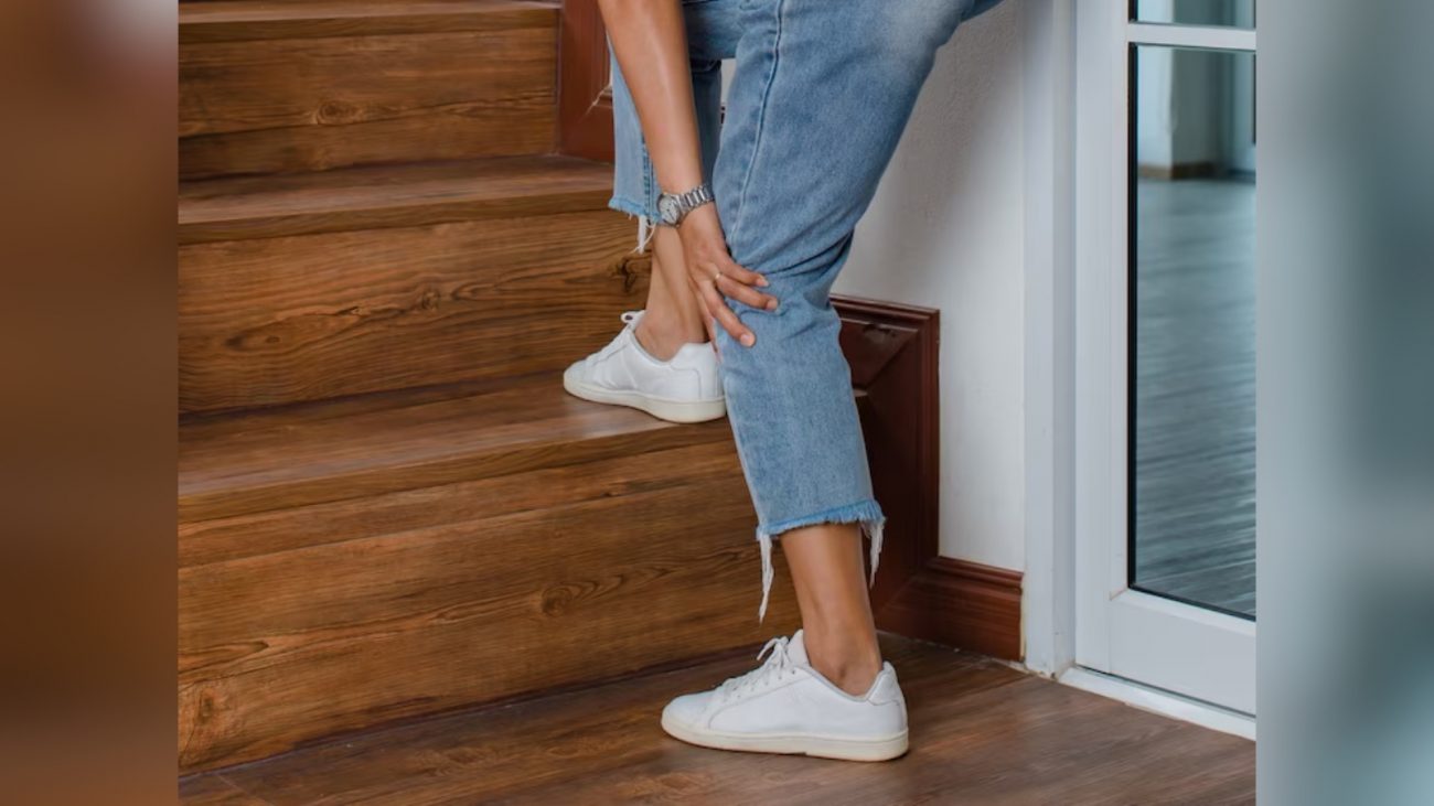 Imagem de pessoa de calça jeans e sapato branco com mão no joelho