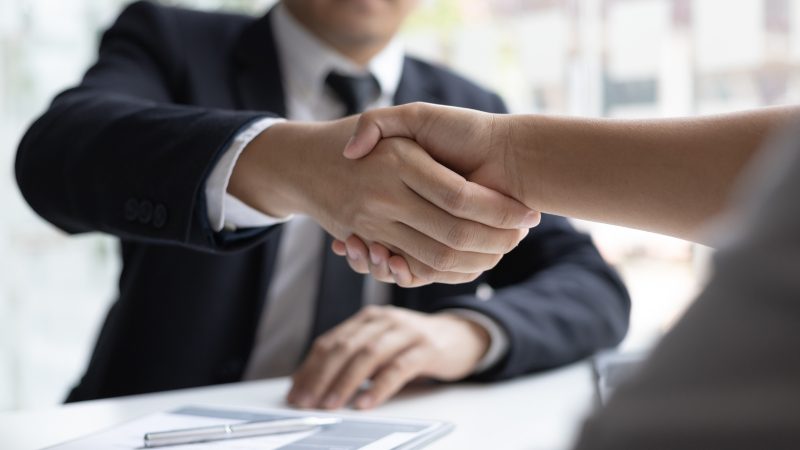 Aperto de mão Pessoa apertando mão de outra em cima de mesa