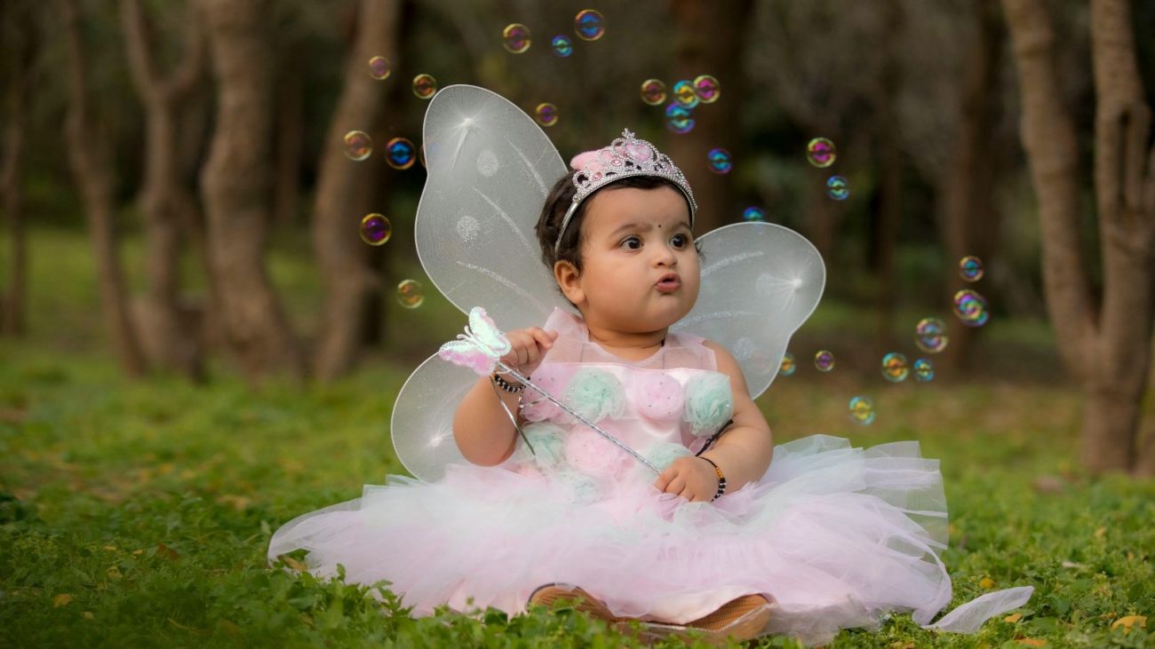 Bebê vestida de fadinha soprando bolhas de sabão