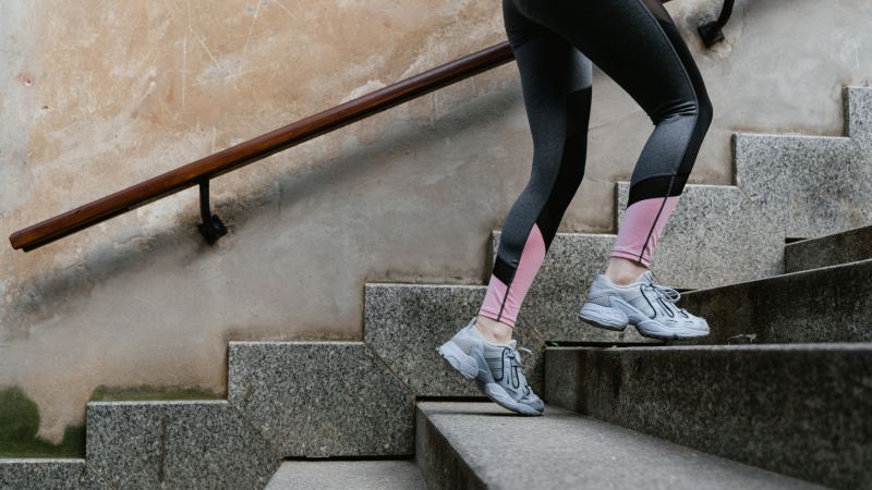Passos Mulher subindo escadas em legging e tênis de academia, contabilizando seus passos diários