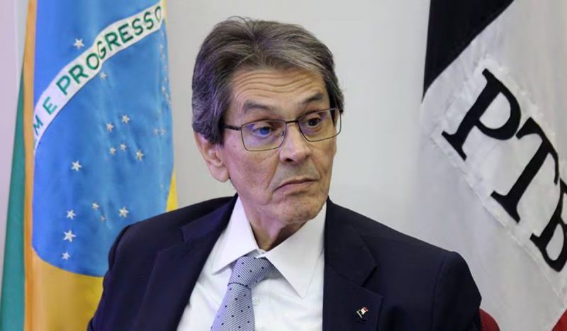 Roberto Jefferson ao centro, com as bandeiras do Brasil (esquerda) e PTB (direita) ao fundo