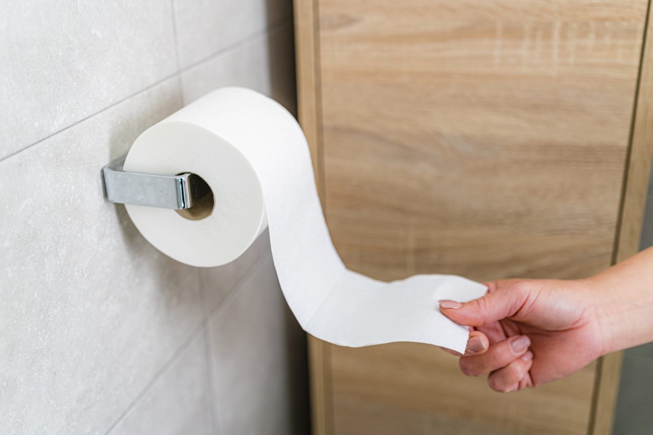 Papel higiênico Pessoa puxando rolo de papel higiênico no banheiro