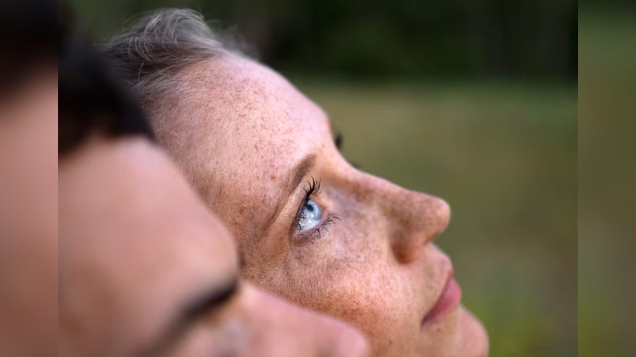 Mulher olhando para cima Mulher com rostos com sardas e olhos azuis olhando para cima ao lado de pessoa