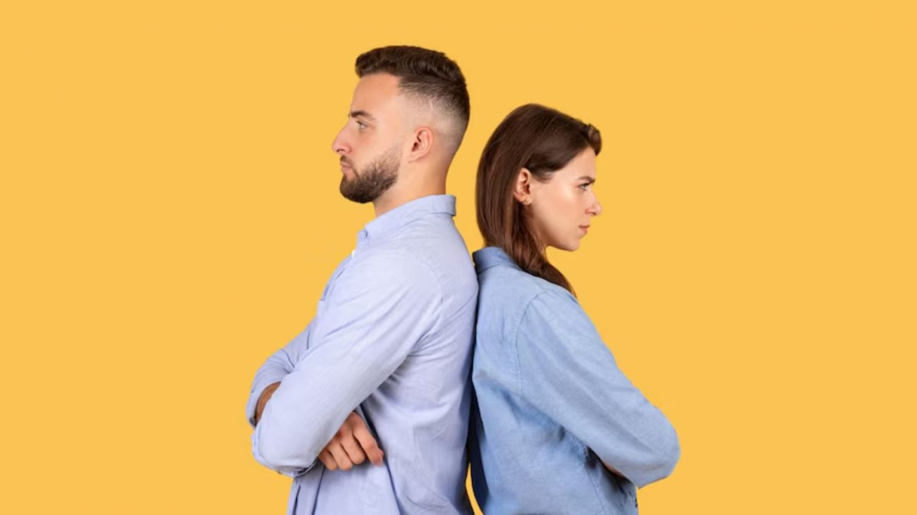 Casal com roupas azuis de costas um para o outro com cara de chateados