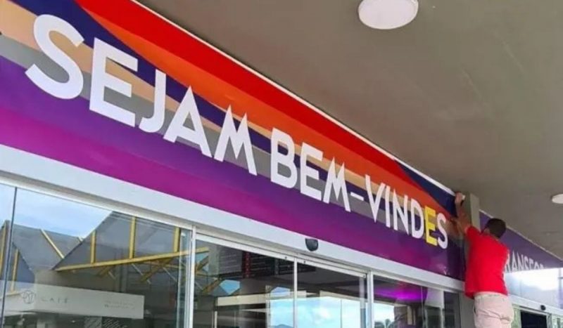 STF derruba decreto que proibia linguagem neutra em SC STF derruba decreto que proibia linguagem neutra em SC, foto mostra faixa escrita "Sejam bem-vindes" em branco, com a letra "e" destacada em amarelo