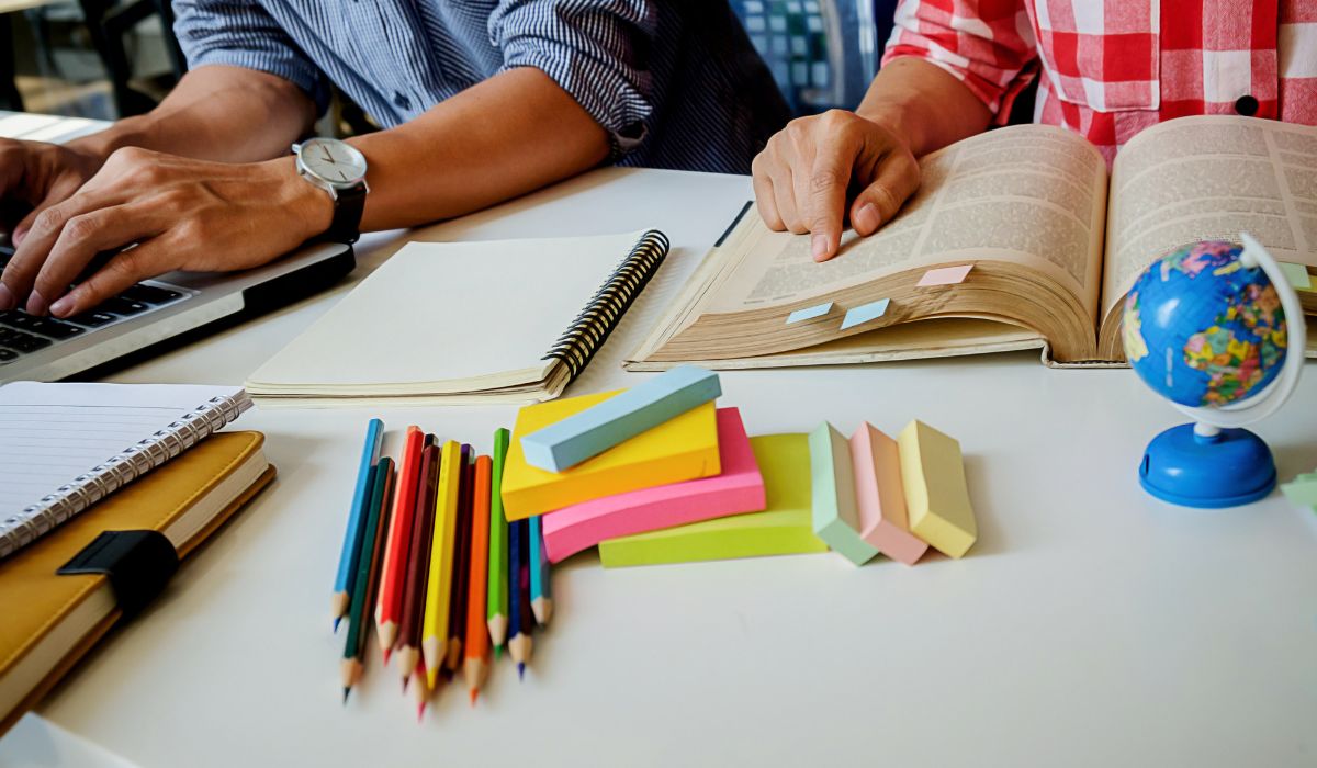 mesa com livros, canetas e post-its