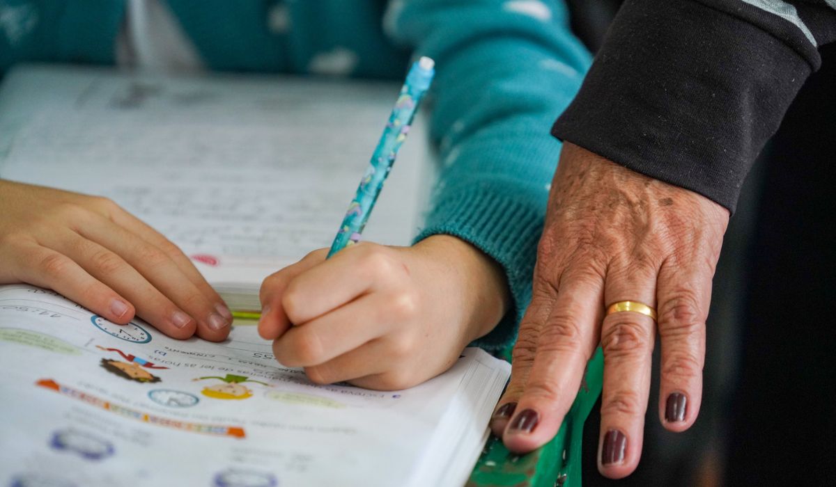 Mãos de aluno e professora em matéria sobre projeto semelhante ao escola sem partido