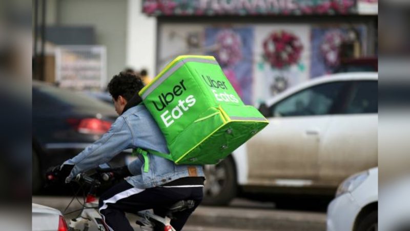 Imagem de motociclista com bolsa da uber eats nas costas