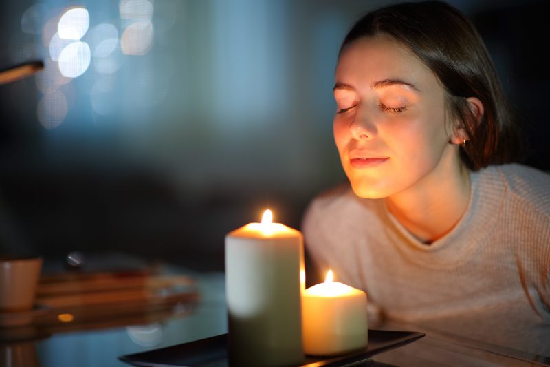 Mulher sentindo o aroma de velas aromáticas antes de dormir