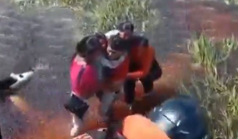 tripulação é resgatada após ficar 36h em pântano com jacarés Tripulação é resgatada após ficar 36h em pântano com jacarés, foto mostra cinco pessoas andando abraçadas em pântano em direção à pessoa com capacete