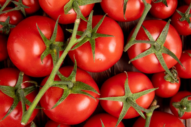 Tomates Tomates ainda com o caule sobre uma mesa de madeira
