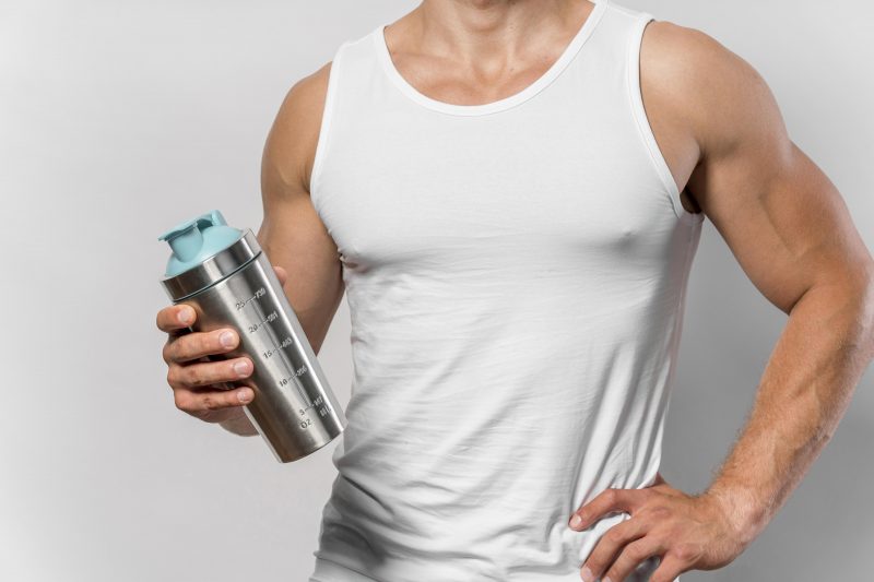 Homem segurando um copo Homem segurando um copo com Whey Protein dentro