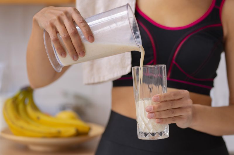 Mulher colocando vitamina em um copo Mulher colocando uma vitamina com Whey em um copo
