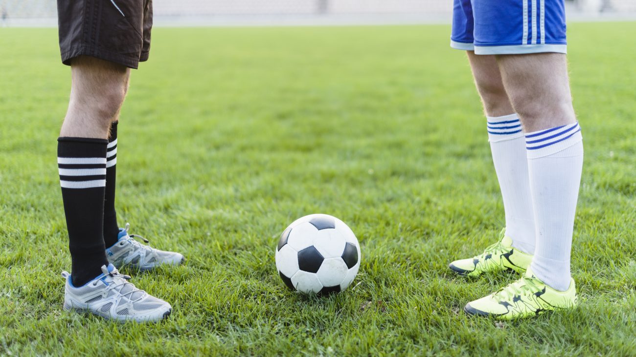 Jogadores de futebol de times opostos em campo com uma bola no meio. Conteúdo sobre aposta 1x2. 