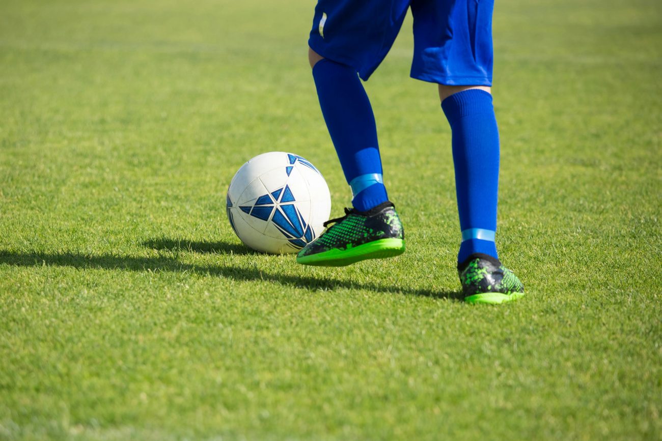 Jogador de futebol chutando bola em campo. Conteúdo sobre aposta simples.