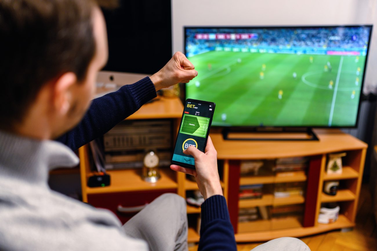 Homem vendo jogo de futebol. Conteúdo sobre apostas ao vivo.