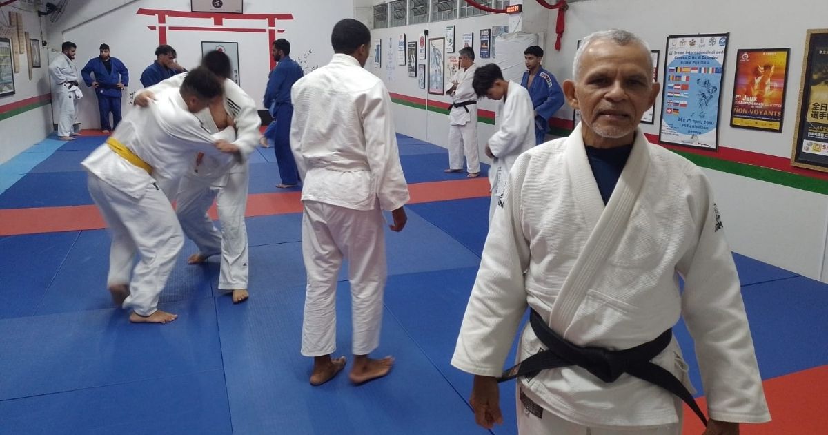 Imagem do homem Carlos Antônio, em um tatame de judô, para fazer referência ao título que é: Faixa-preta em judô volta à sala de aula após 60 anos