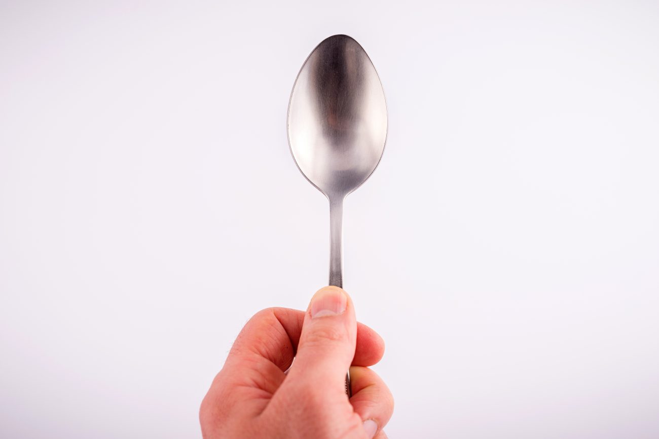 Homem segurando colher de inox para tirar cheiro de alho das mãos