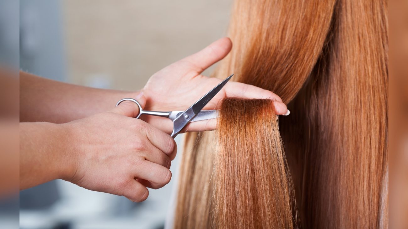 Pessoa ruiva com cabelo em mão de pessoa com tesoura