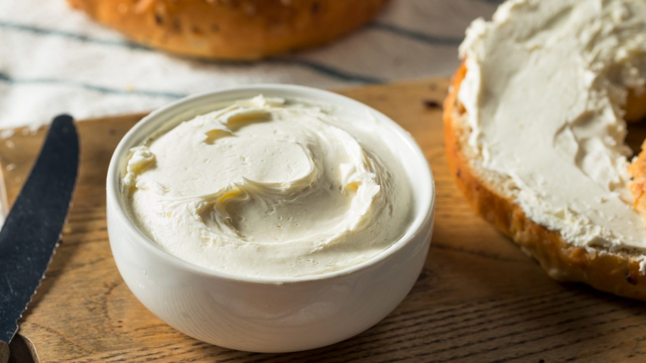 imagem de cream cheese com faca e pão próximo