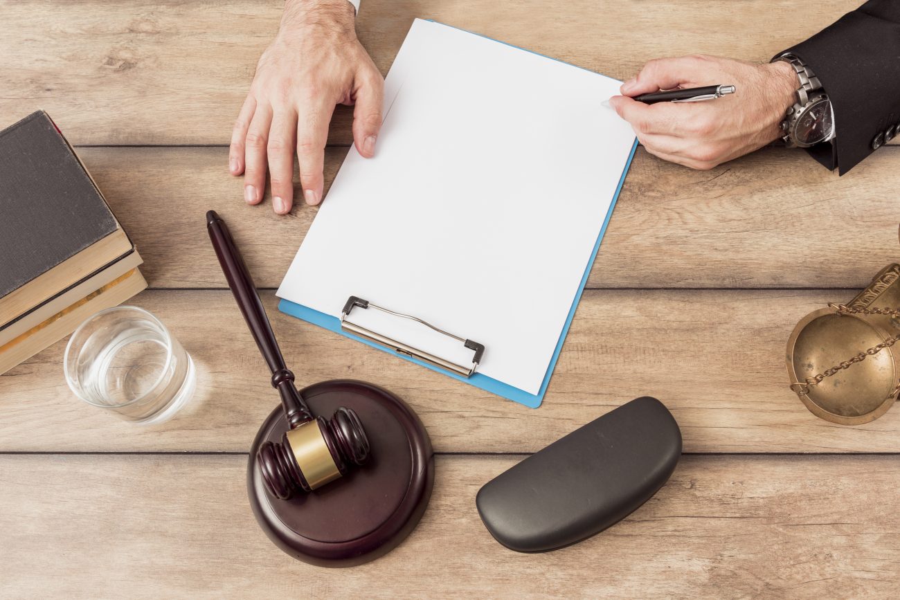 Pessoa escrevendo em folha branca, simbolizando estudo para concurso para promotor de Justiça