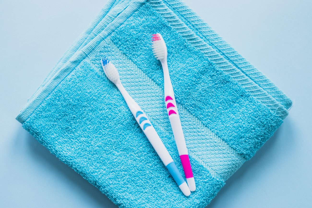 Escovas de dente azul e rosa sobre uma toalha de rosto