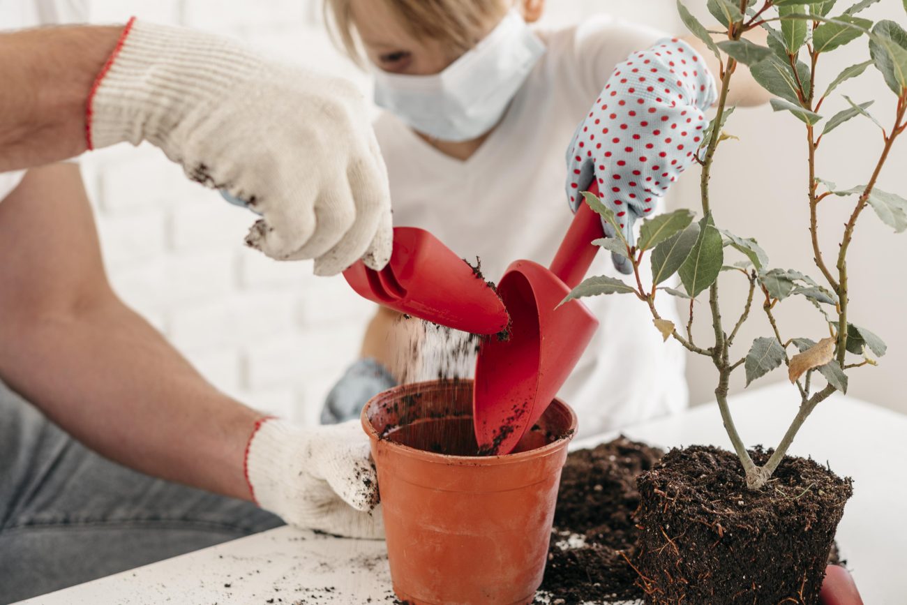Pai e filho colocando terra em um vaso para plantar uma nova planta