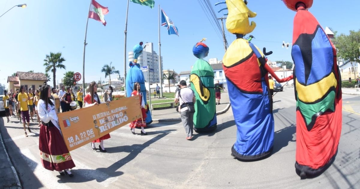 Imagens de um desfile realizado por artistas, para fazer referência ao festival de teatro que abriu a seleção de grupos para participarem das apresentações