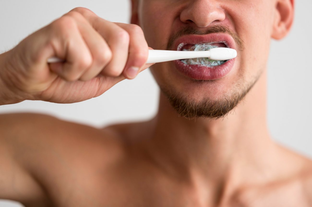 na foto com a escova na mão homem encontra o momento ideal do dia para escovar os dentes e cuidar da higiene bucal