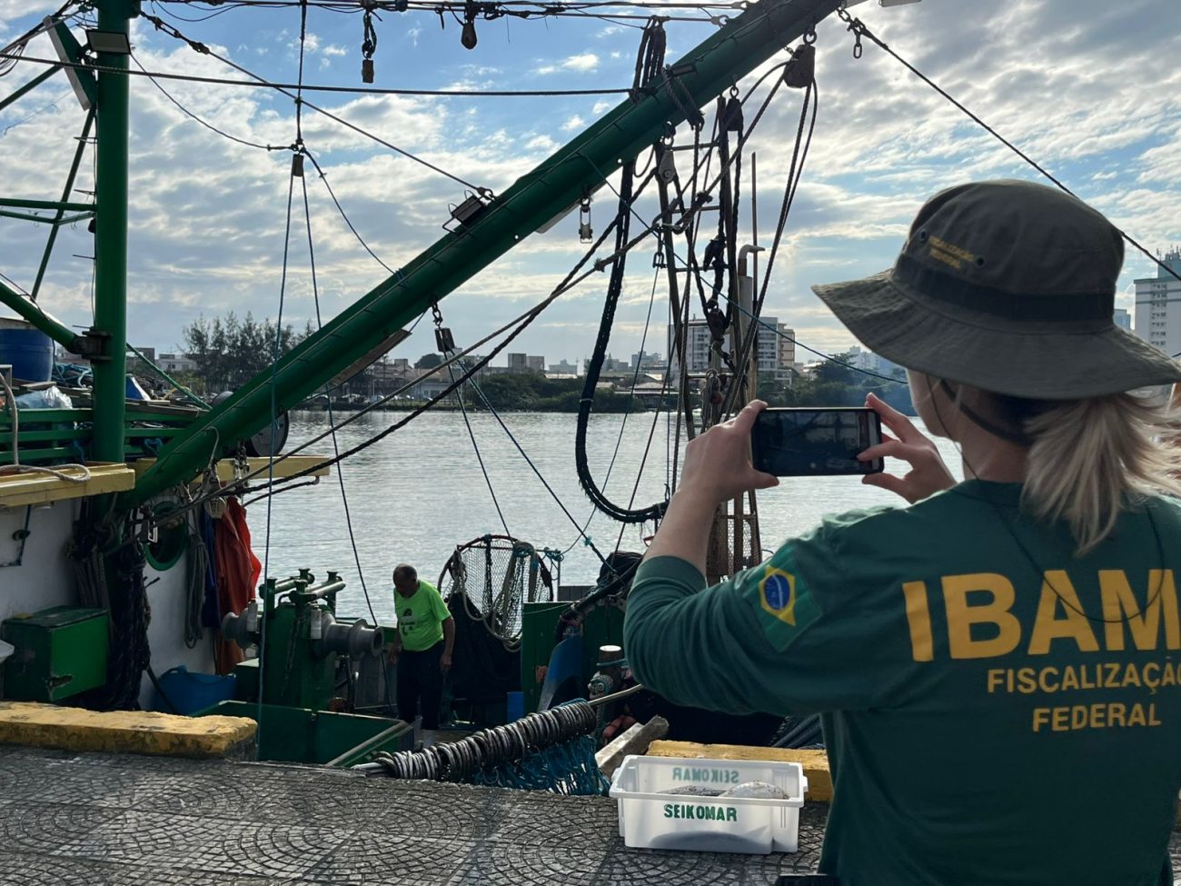 Foto mostra fiscal do Ibama tirando fotos da embarcação com tainha ilegal em Itajaí