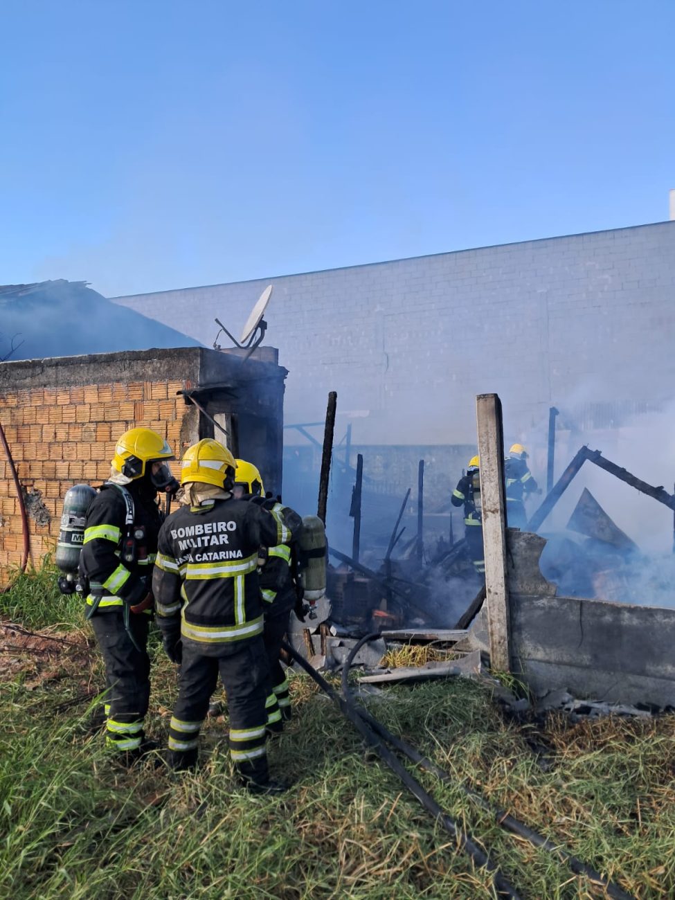 Foto mostra bombeiros contendo as chamas no local.