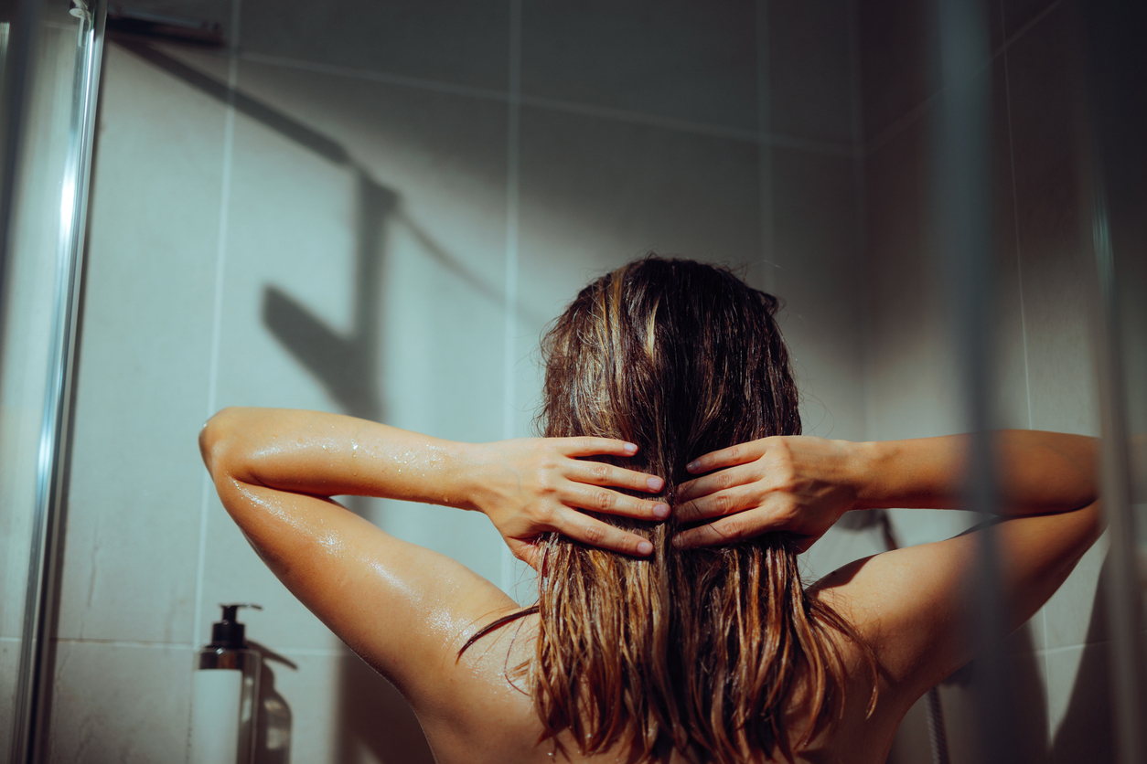 Mulher exnaguando cabelo no chuveiro para tirar vinagre no cabelo