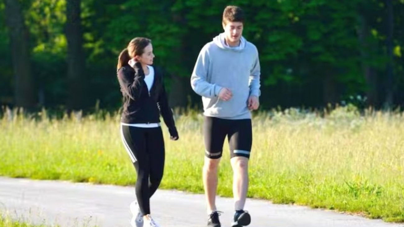 na foto aparece um casal de homem e mulher e uma pessoa anda sempre olhando para o chão