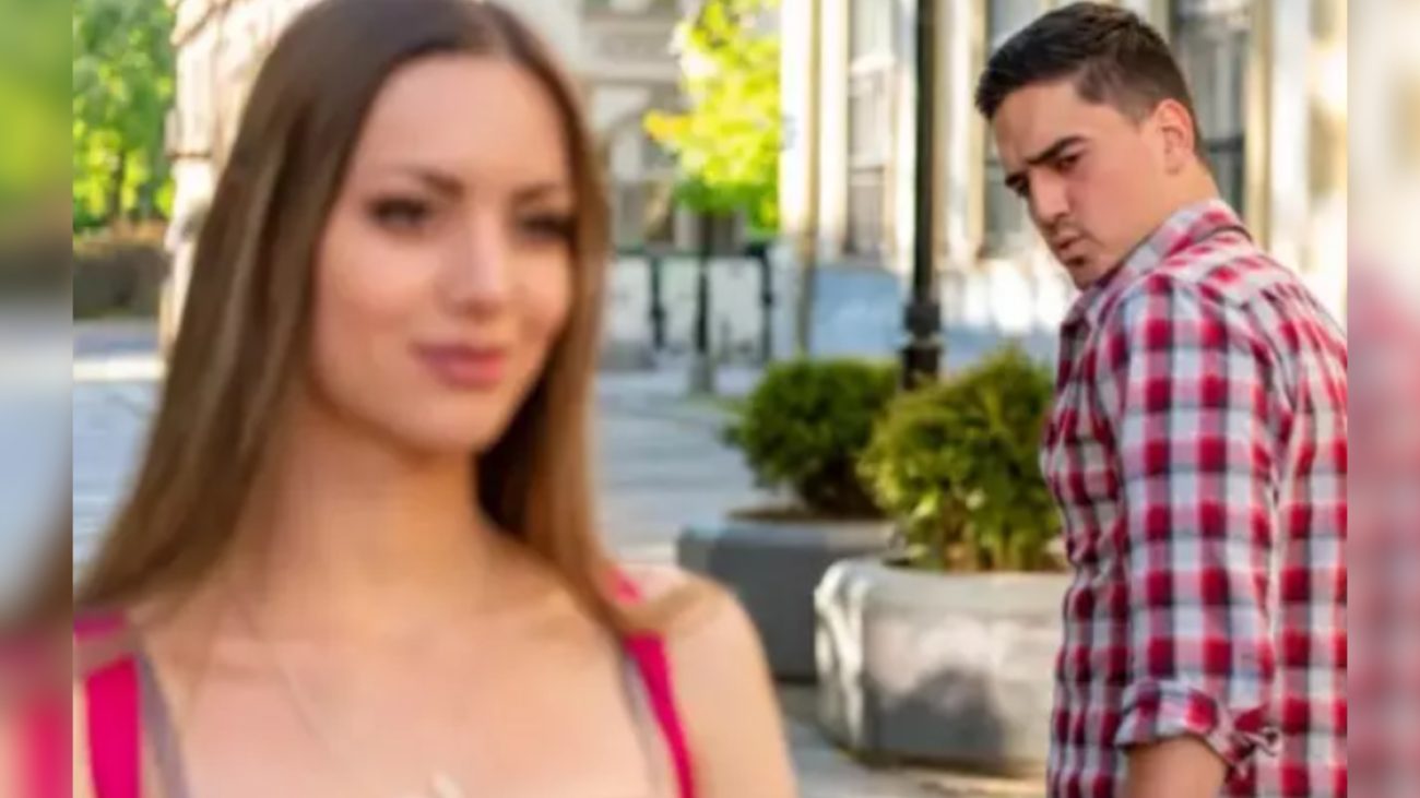 Cena que captura um momento de ciúmes e incompreensão entre um jovem homem e uma mulher em ambiente ao ar livre, com cenário urbano e vegetação ao fundo.