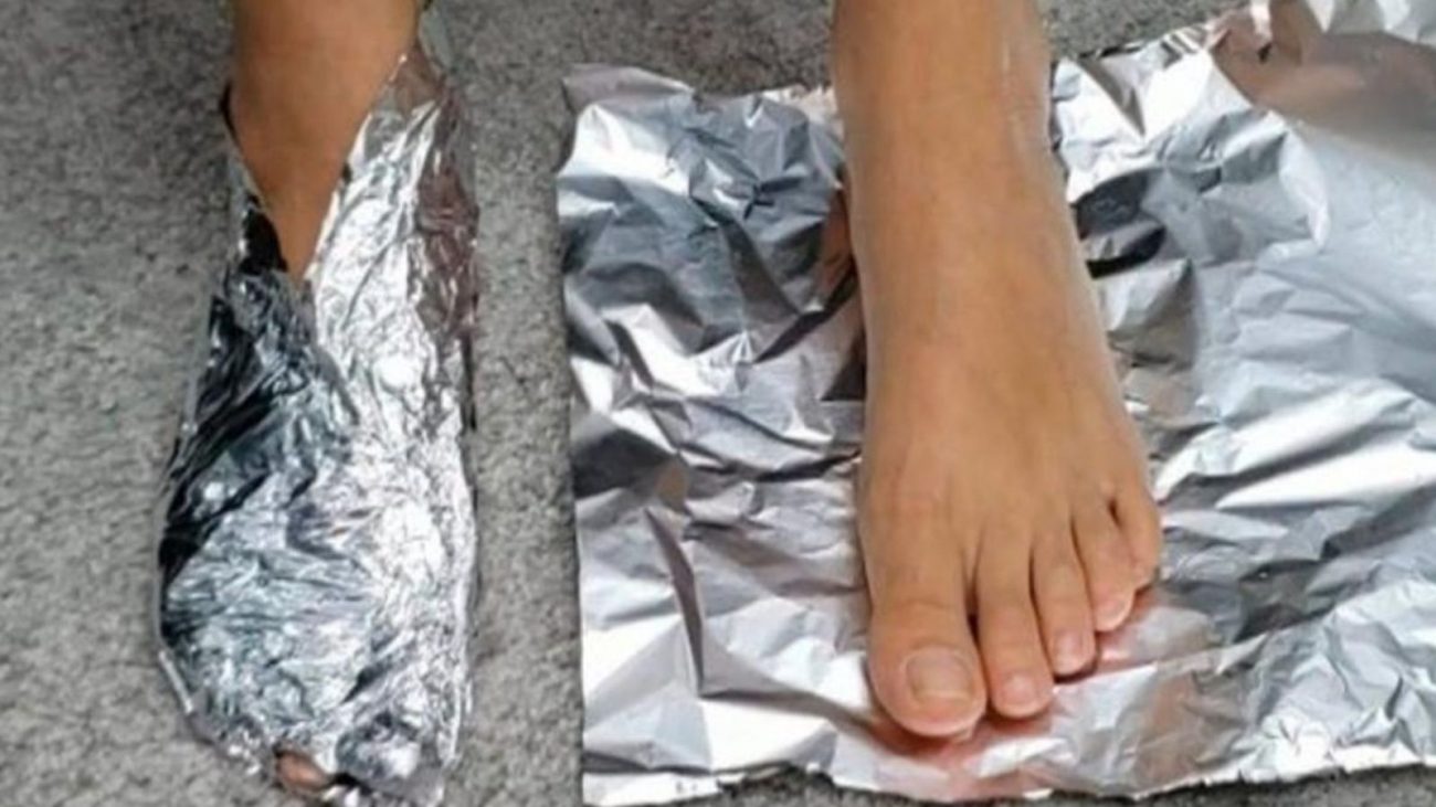 na foto aparecem dois pés de uma pessoa que ficam enrolando os braços e as pernas no papel alumínio