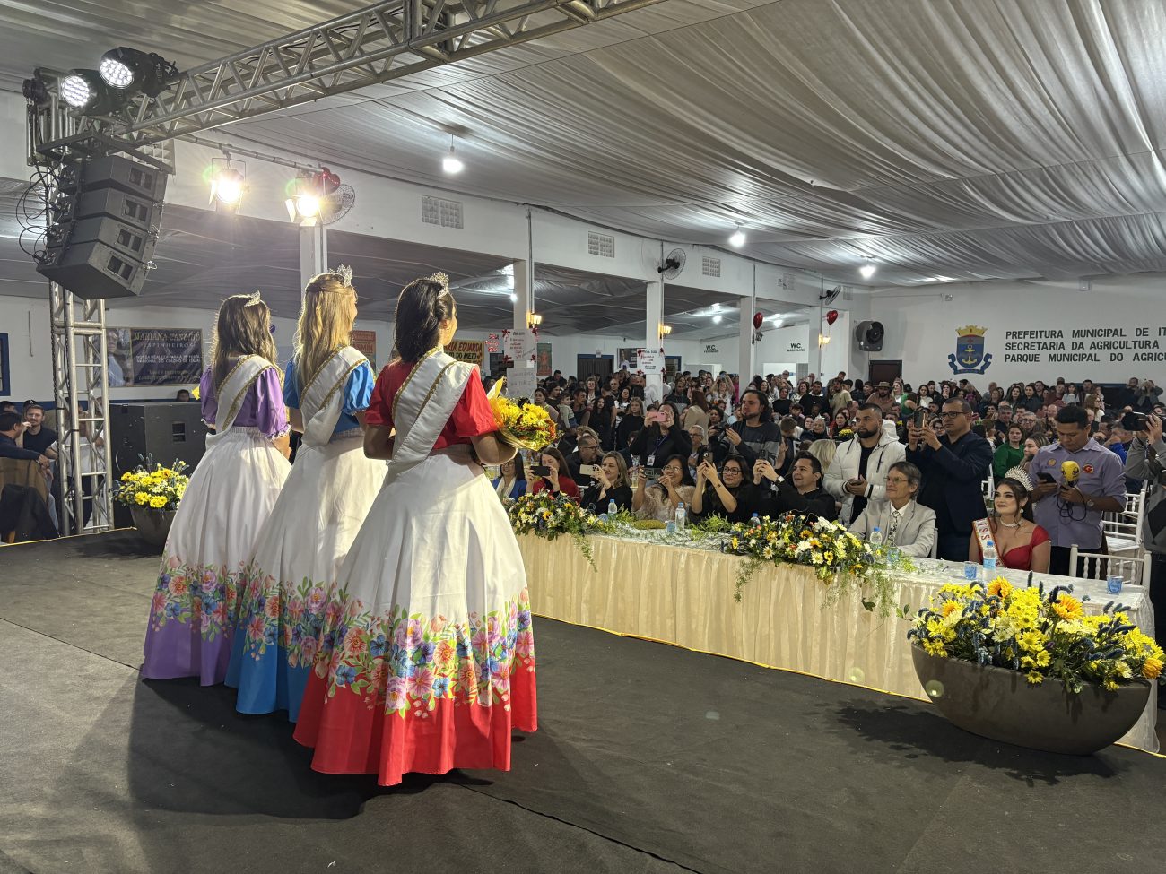 Foto mostra as 3 integrantes da realeza da Festa Nacional do Colono de Itajaí voltadas ao público