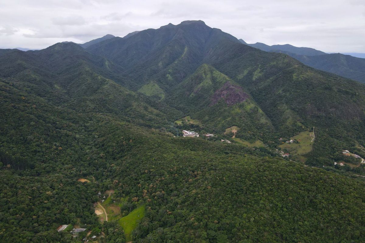 Foto da verdejante Serra do Tabuleiro com vários picos. O céu está nublado.