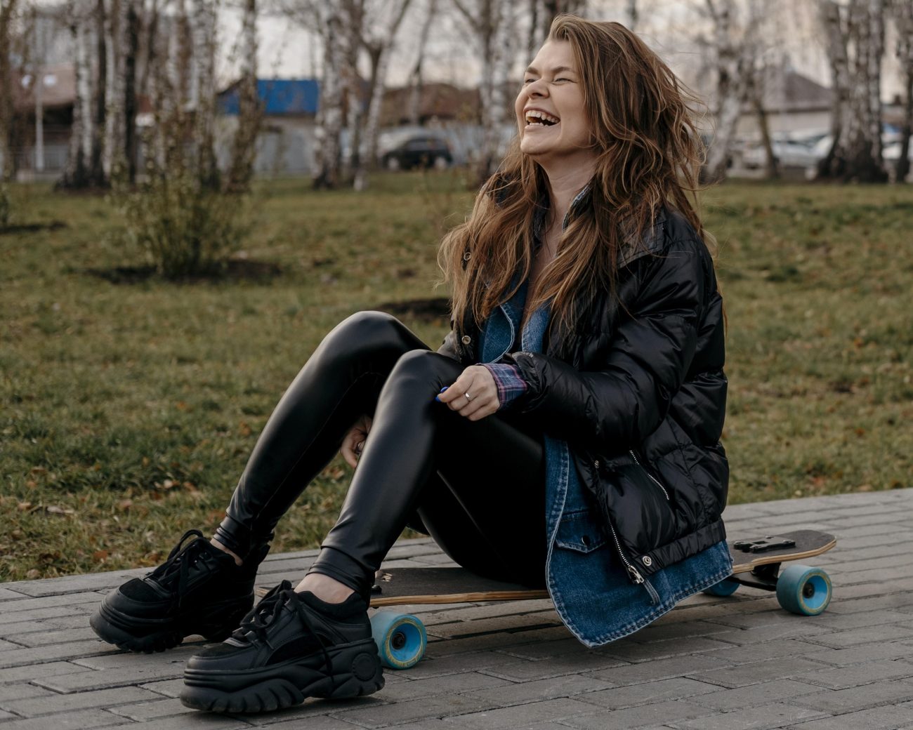Mulher com tênis sentada em um skate em um parque