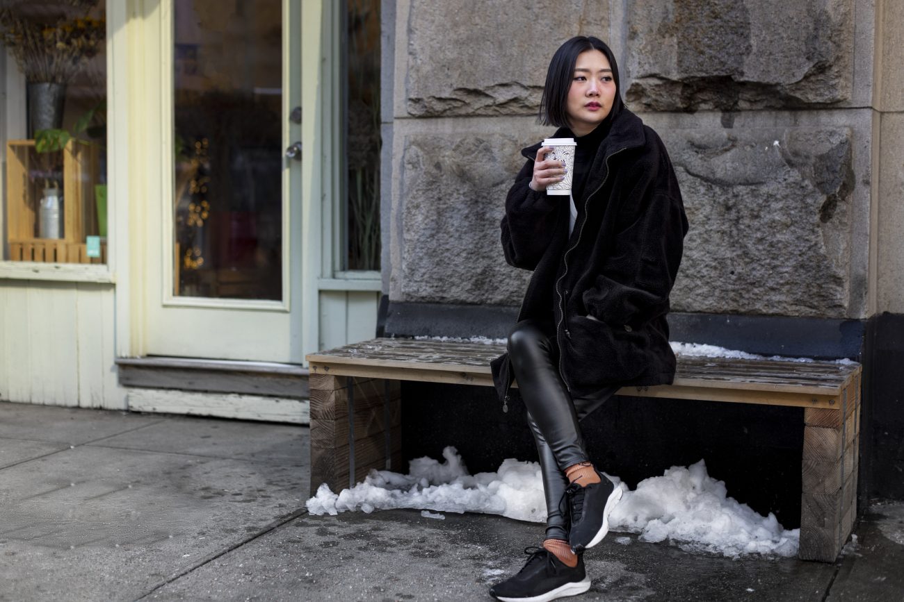 Jovem usando tênis no frio enquanto toma um café na rua