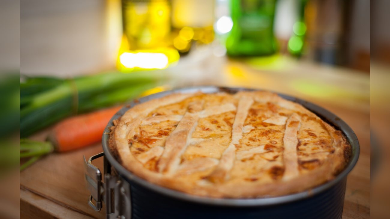 Imagem de uma deliciosa pizza caseira de queijo e frango, assada em forno tradicional, com crosta dourada, apresentada sobre uma bancada de madeira.