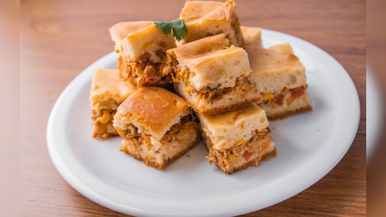 Deliciosos pedaços de barfi, um doce tradicional indiano feito com leite em pó, açúcar e especiarias, servidos em um prato branco sobre uma mesa de madeira.