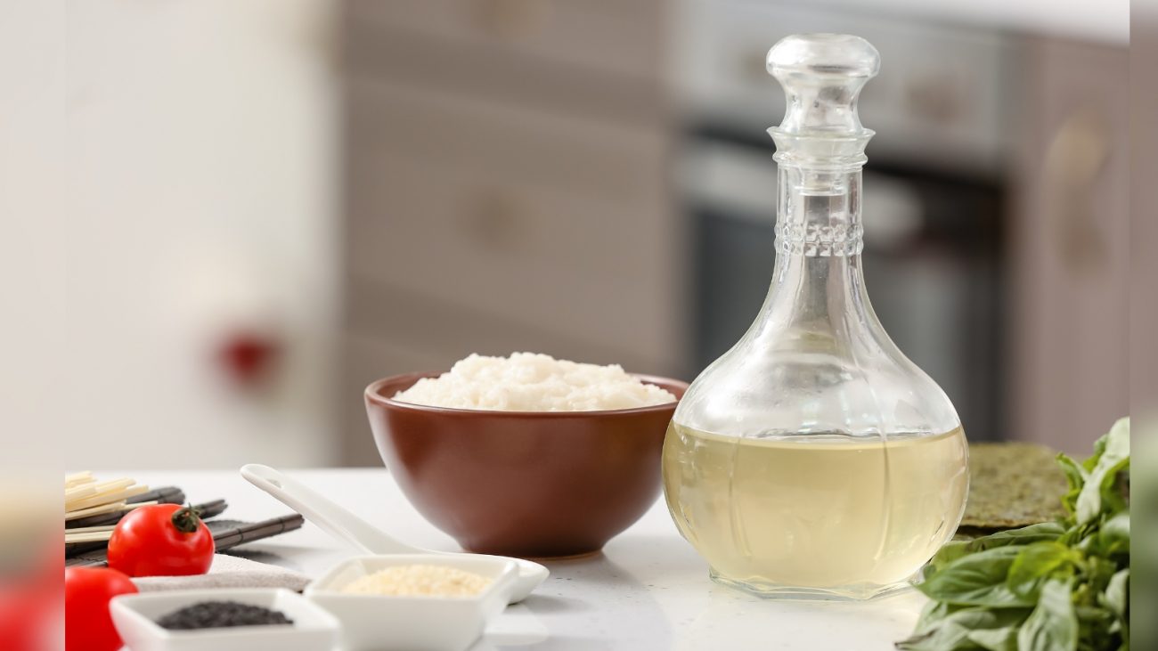 Vinagre branco em pote e sal dentro de pote rodeado por verduras e legumes