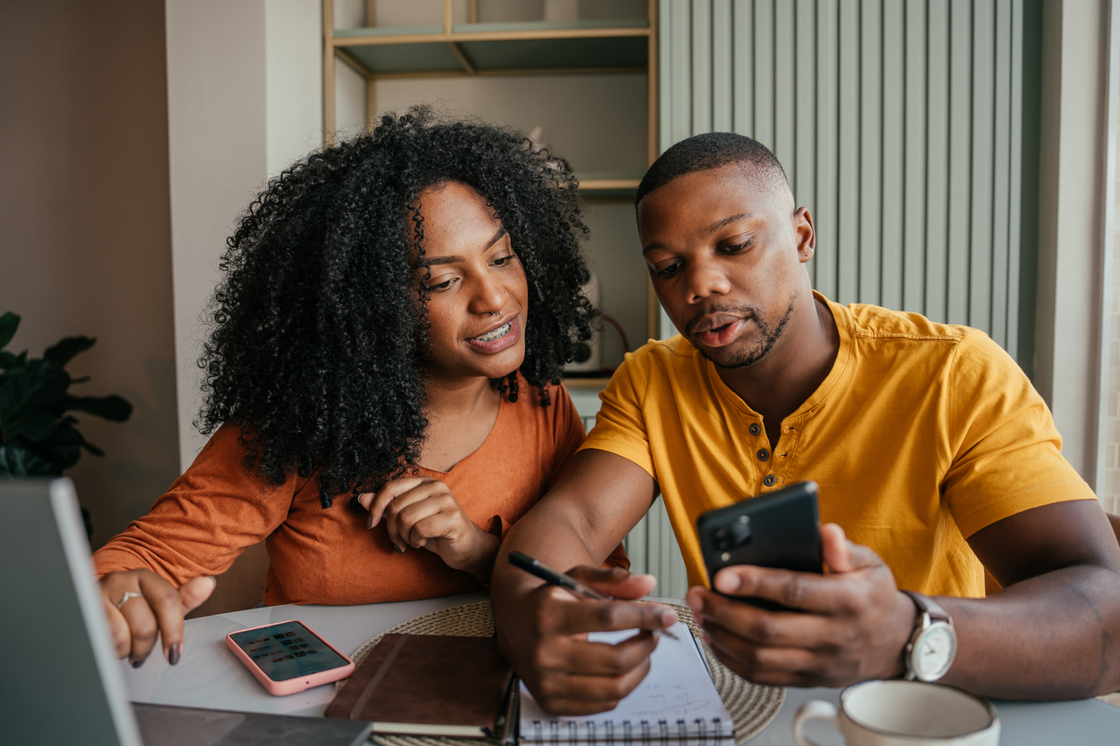 Homem e mulher sentados olhando para o celular com planejamento e viagem