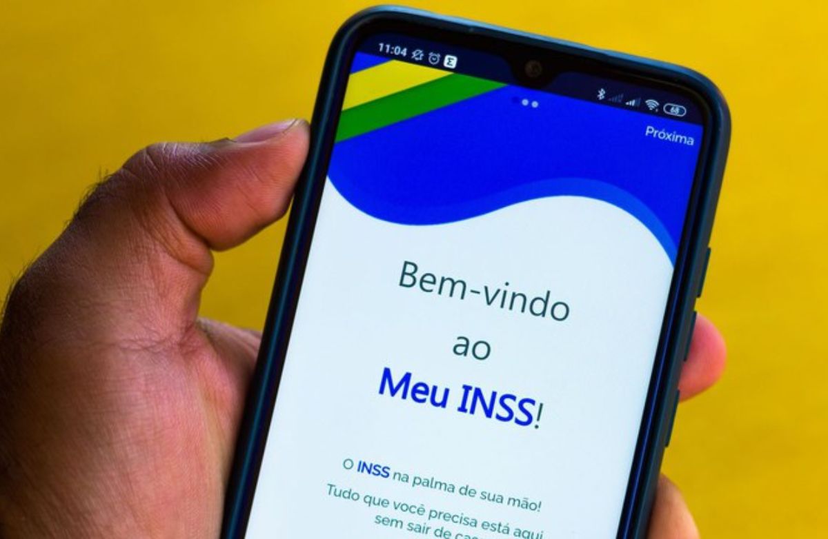 Mão segurando celular com o aplicativo do INSS aberto