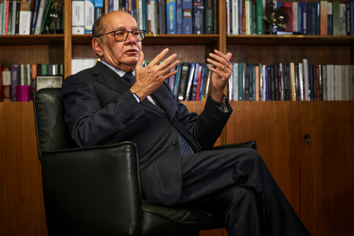 Ministro Gilmar Mendes. Ele é um homem careca, que usa óculos, veste terno e está sentado em uma poltrona preta. Atrás dele, uma estante com livros.